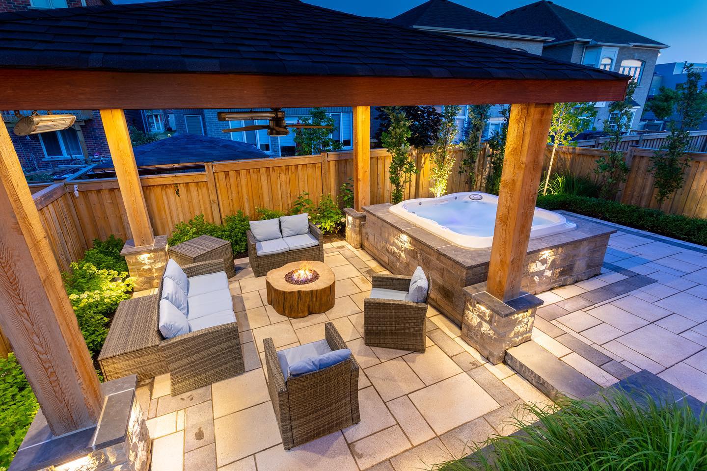 Covered seating and stone-clad hot tub at dusk