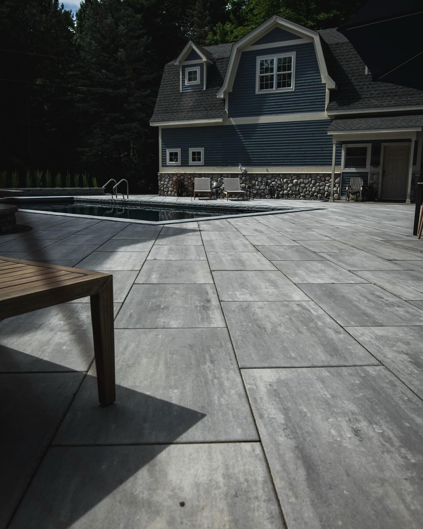 Poolside paving beside a wooded home
